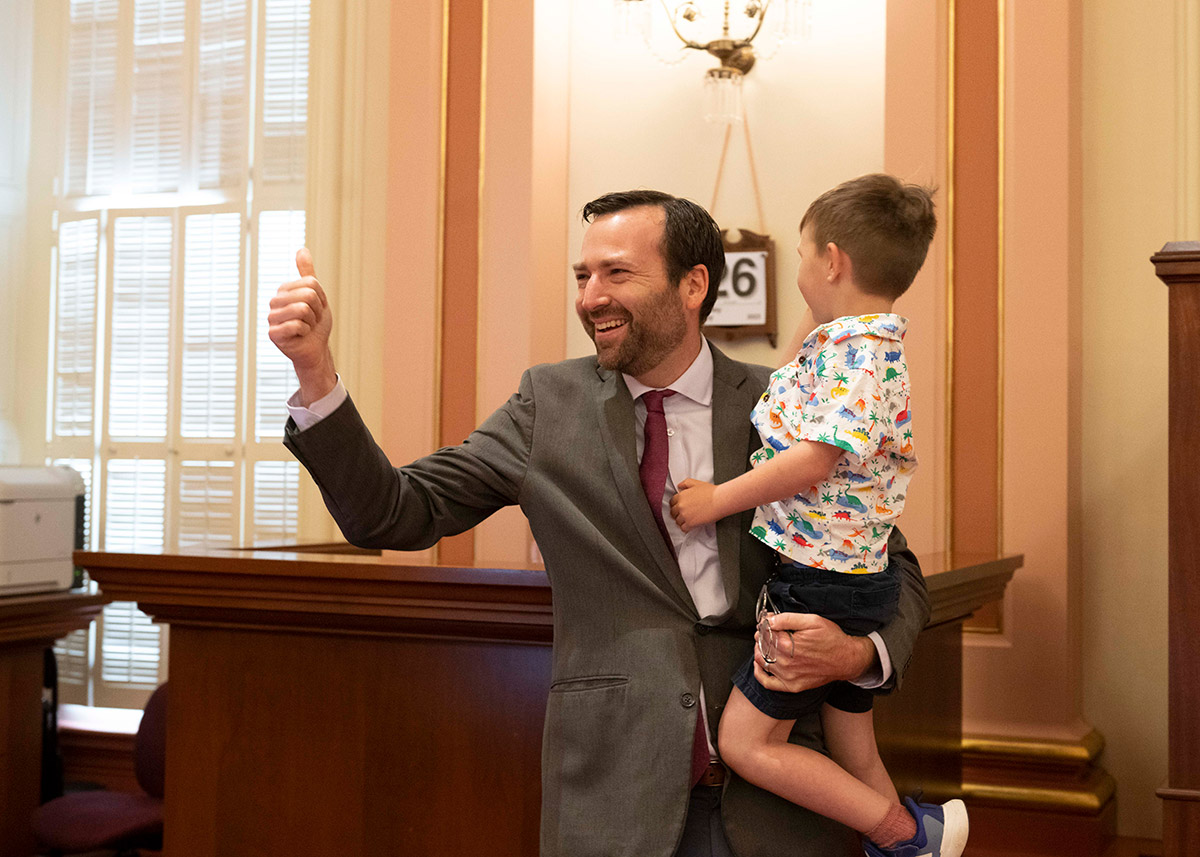 Senator Allen holds his son on the floor while giving a thumbs up.